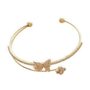 Double-layered gold cuff bracelet with zircon butterfly and clover charms on white background