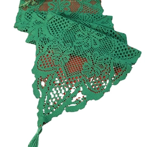 Green lace Christmas table runner with intricate floral patterns and decorative tassels