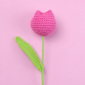 Detailed view of hand-knitted pink tulip flower made of yarn on a soft pink background