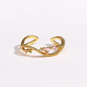 Détail d'une bague dorée ondulée avec cœur rose et cristaux étincelants multicolores
