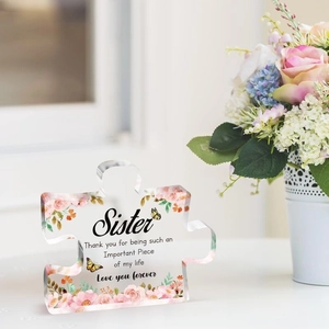 Detail of puzzle-shaped acrylic plaque with pink floral patterns and sister quote