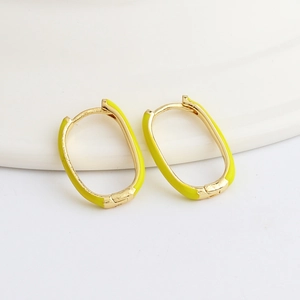Detailed macro view of gold oval earrings with vibrant yellow enamel finish