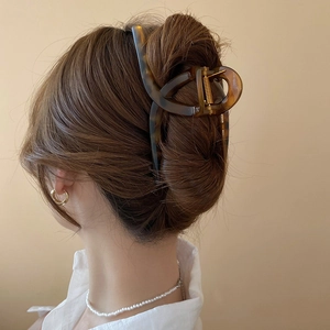 Detail view of large leopard print hair claw clip on a woman's bun with elegant styling