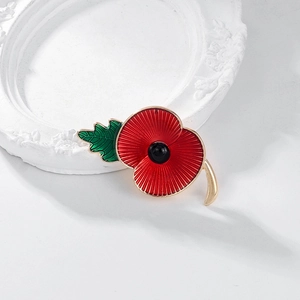 Elegant red enamel poppy brooch with green leaf detail on a white vintage photo frame