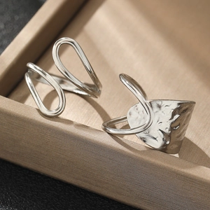 Detail of silver irregular hammered metal ring and dual-loop open ring on gold silk fabric