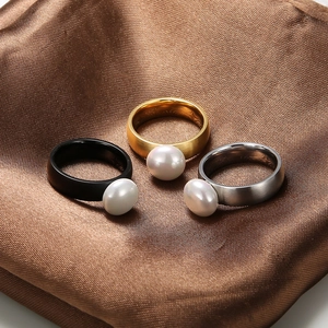 Three pearl rings in gold, silver, and black finish on brown satin background