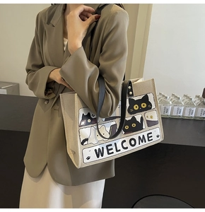 Close-up of beige canvas tote bag featuring cute cartoon cat prints and welcome text
