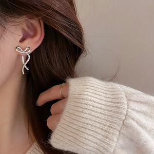 Elegant bow-shaped stud earrings with sparkling crystals and silver plating on model
