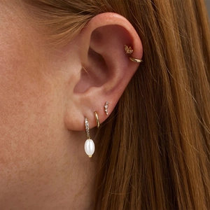 Detail of layered gold earrings with white pearls and sparkling cubic zirconia stones