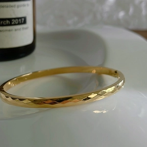 Detail view of 18k gold plated stainless steel bangle with geometric faceted texture