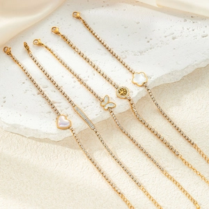 Close-up of gold titanium steel bracelets with diamond-encrusted heart and butterfly charms