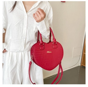 Détail du sac à main rouge en forme de cœur avec texture croco et logo Fashion
