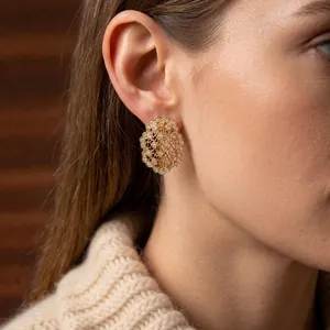 Elegant gold oval hollow stud earrings with sparkling zircons worn by a model