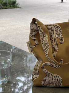 Gros plan d'un sac cabas en toile jaune moutarde avec imprimé léopard et étiquette