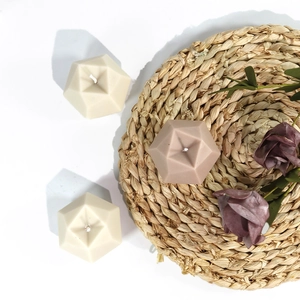 Flat lay of geometric diamond cut scented candles on woven mat with dried flowers