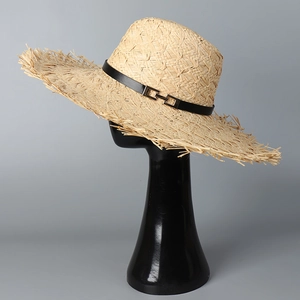 Detail of raffia sun hat with black leather band and raw frayed edge trim