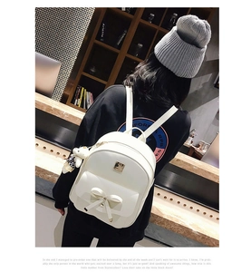 Detailed view of a white bow-knot PU leather backpack with a cute plush bear pendant