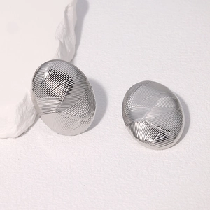 Gros plan de boucles d'oreilles ovales en acier inoxydable avec motif texturé croisé