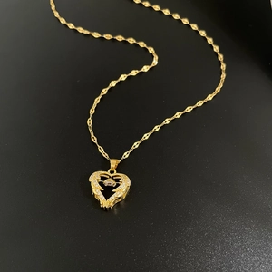 Detailed close-up of a gold heart pendant with sparkling crystals on a textured chain