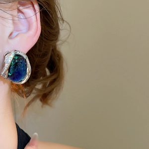 Vue détaillée de boucles d'oreilles géométriques en résine bleu-vert portées sur l'oreille