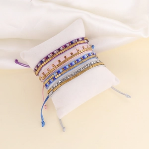Bohemian hand-woven beaded bracelets on display pillow in assorted pastel colors