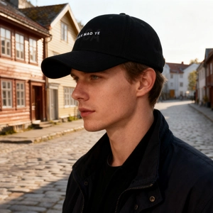 Classic black cotton baseball cap with white embroidery worn by model in street setting