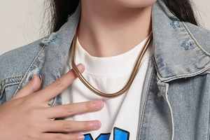 Gros plan d'un collier chaîne serpent dorée élégant porté par un mannequin