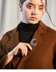 Close-up of a crescent moon brooch with purple crystals on a wool coat lapel