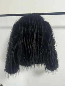 Detail shot of fluffy black faux fur coat texture with voluminous feathered design