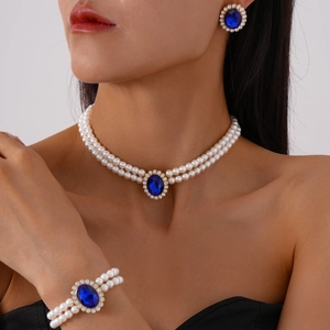 Close-up of double-layer pearl necklace with oval blue gemstone and diamond halo detail