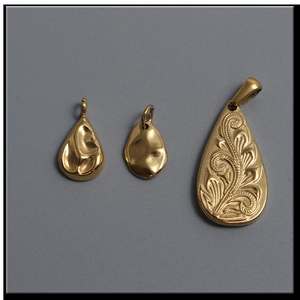 Detailed view of 14k gold teardrop and leaf pendants showing embossed vein textures
