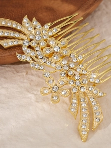Makroaufnahme von goldenem Haarkamm mit funkelnden Strassblumen und Schleifen-Details