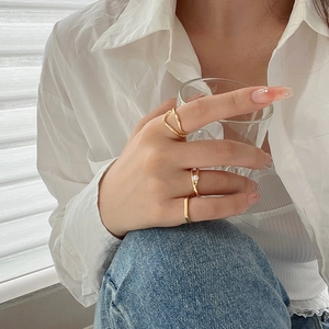 Close-up of three gold rings set featuring irregular curves, pearls and crystals