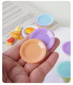 Mini assiettes colorées en plastique pour maison de poupée tenues dans la main