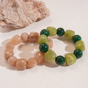 Detail of pink and green acrylic beaded bracelets with marble texture on white background