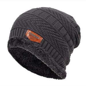 Detail view of winter knit beanie with thick grey faux fur lining and brown leather patch
