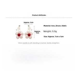Close-up of pearl drop earrings with red polka dot flower and zircon details