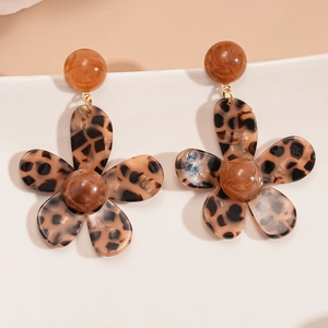Macro detail of brown leopard print resin flower earrings on a white ceramic dish