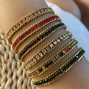 Close-up of stacked gold plated bracelets featuring colorful round cut crystal settings