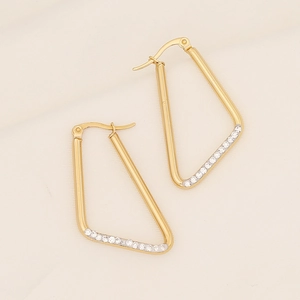 Detail of gold geometric triangle earrings with micro-pave white zircons on beige fabric