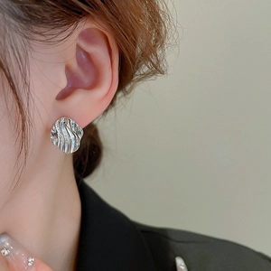 Close-up of silver irregular water ripple earrings worn by a model for elegant look