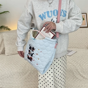 Detail of light blue quilted tote with black cat embroidery and pink shoulder strap