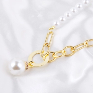 Detail of baroque pearl pendant with rhinestone inlay on gold chain against silk