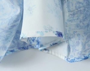 Macro shot of blue floral print and fine stitching details on a summer dress fabric