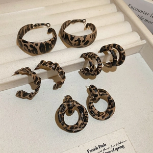 Macro detail of four vintage leopard print earring sets on a beige jewelry display tray