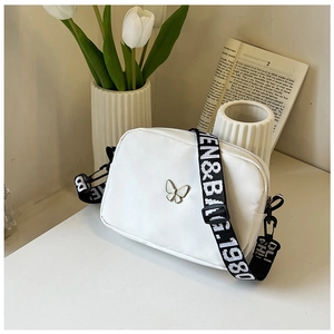 White nylon crossbody bag with wide letter strap and silver butterfly detail