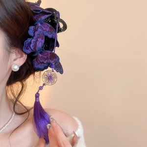 Dettaglio del fermaglio per capelli a farfalla ricamata viola con lunghe nappe