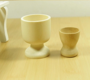 Detail of two unpainted natural wood egg cups in different sizes on a light wooden table