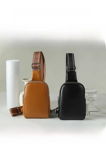 Detail of compact crossbody chest bags in caramel and black faux leather with wide straps