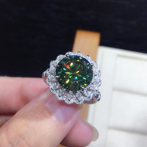 Macro shot of silver sunflower ring featuring a large green moissanite with halo diamonds